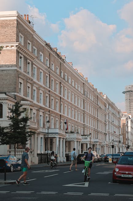 A wide view of a historic residential building with a cream-colored facade, multiple rows of large sash windows, and decorative architectural details, situated on a London street under a partly cloudy